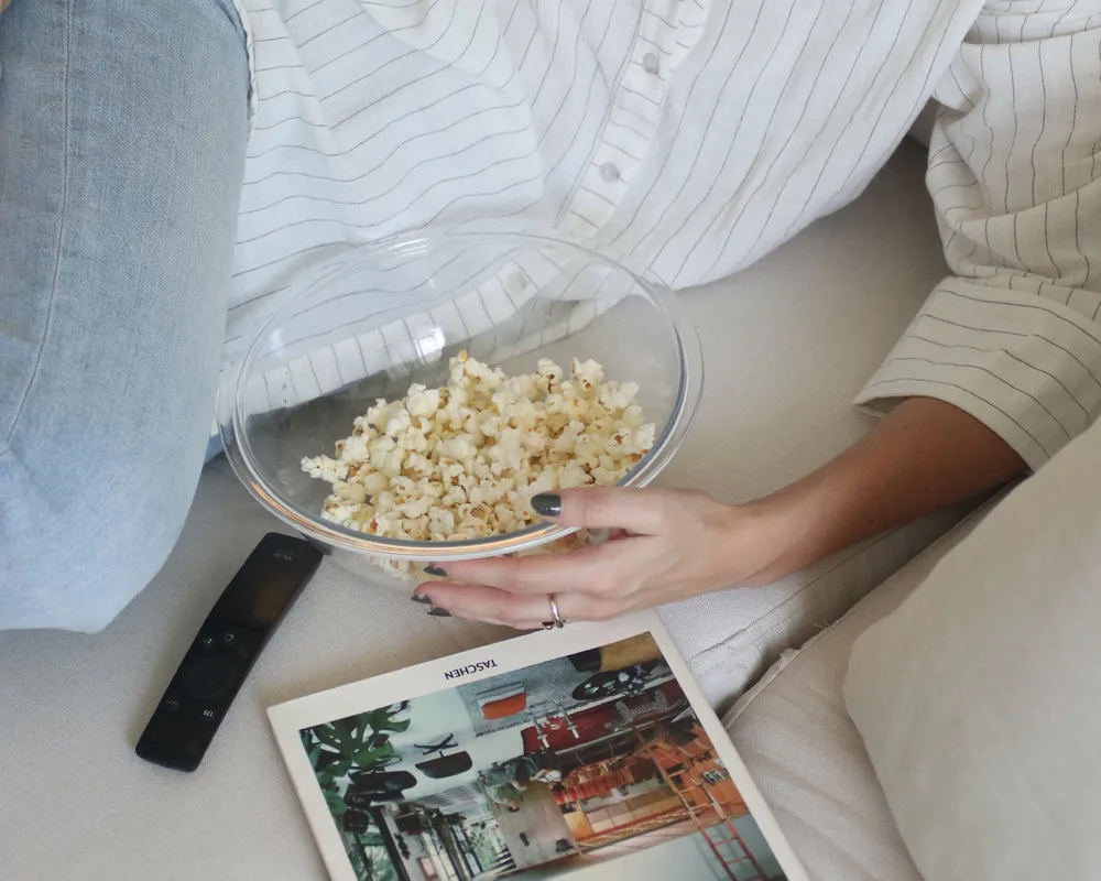 Pipoca e um livro sobre o assento do sofá, num fim de tarde em casa